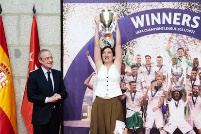 La presidenta de la Comunidad de Madrid, Isabel Díaz Ayuso, levanta la miniréplica de la Copa de Europa que le acaba de entregar el presidente del Real Madrid, Florentino Pérez.