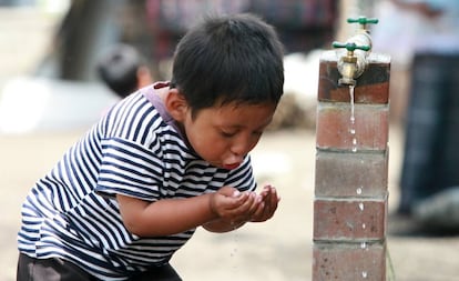 Niño bebe de una fuente de agua en Sololá, Guatemala.