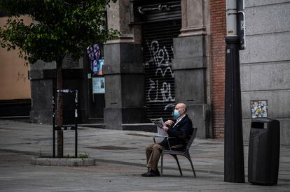 Un hombre lee un periódico en una calle de Madrid, este martes. ÁLVARO GARCÍA