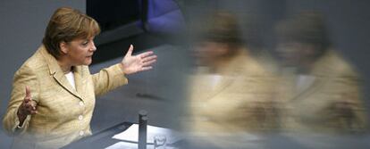 La canciller alemana, Angela Merkel, reflejada en un cristal de una ventana del Parlamento durante su intervención ayer en Berlín.