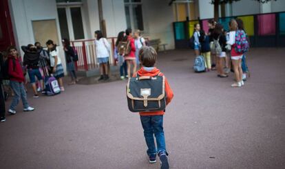 Un ni&ntilde;o con mochila en el patio de un colegio. 