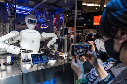 A visitor takes a photo of a Barman 5G waiter robot mixing drinks during the Mobile World Congress 2022
