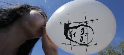 Una manifestante anti-Putin infla un globo con la cara del presidente, en una protesta en Moscú.