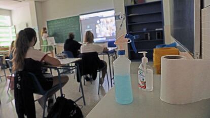 Productos desinfectantes colocados en los pupitres desde donde los alumnos atienden a las clases semipresenciales impartidas en un colegio de Madrid.