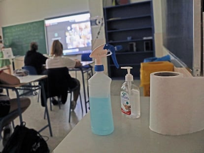 Productos desinfectantes colocados en los pupitres desde donde los alumnos atienden a las clases semipresenciales impartidas en un colegio de Madrid.