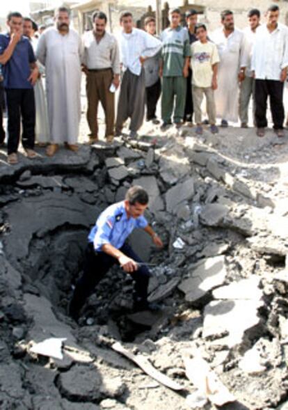 Un policía iraquí camina por el cráter abierto por la explosión de un coche bomba en Mosul.