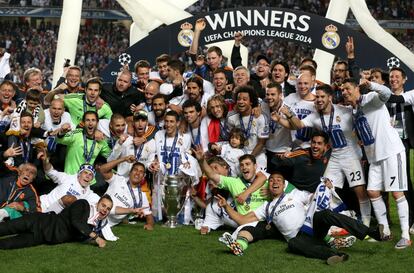 Jugadores y t&eacute;cnicos del Real Madrid posan en el campo con el trofeo. 