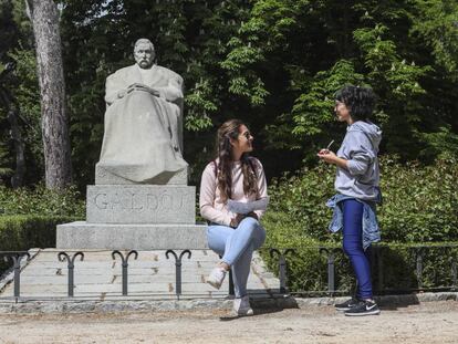 Dos chicas charlan junto a la estatua de Pérez Galdós en el Retiro.