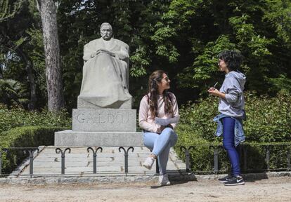 Dos chicas charlan junto a la estatua de Prez Galds en el Retiro.