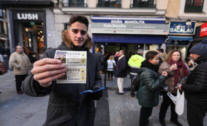 Una persona enseña el décimo de lotería de Navidad que ha conseguido comprar en la administración Doña Manolita (Madrid), tras dos horas y media de espera.