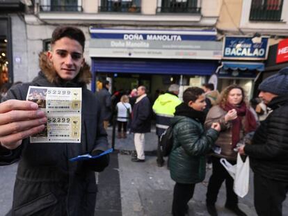 Una persona ense&ntilde;a el d&eacute;cimo de loter&iacute;a de Navidad que ha conseguido comprar en la administraci&oacute;n Do&ntilde;a Manolita (Madrid), tras dos horas y media de espera.