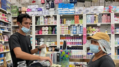 Comerciante do centro de Caracas vende um perfume em dólares para uma cliente no sábado.
