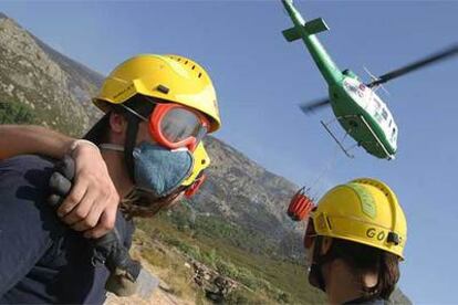 Los bomberos, apoyados por un helicóptero, trabajan en un incendio en Bustarviejo.