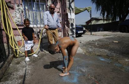 Un niño se baña para eliminar las manchas de pintura, durante la accion de Boa Mistura en la Cañada Real.