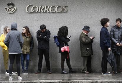 La Junta Electoral ha ampliado el plazo del voto por correo hasta el viernes a las 14:00 horas debido a la gran demanda de solicitudes. En la imagen, la gente forma una fila en el exterior de la oficina de Guzmán el Bueno, en Madrid.