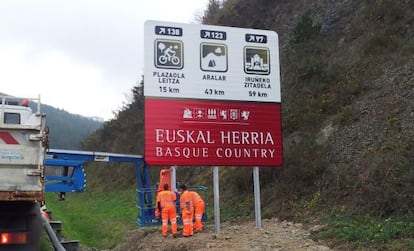 Operarios colocan un cartel con el lema 'Euskal Herria-Basque Country' en la carretera que une Gipuzkoa con Navarra.