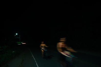 Unas ciclistas transitan una calle mal iluminada entre Puerto Viejo y playa Cocles.