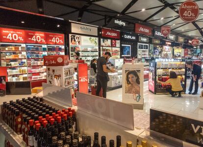 Viajeros comprueban productos en una tienda libre de impuestos del aeropuerto de el Prat (Barcelona).