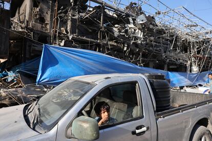 Un niño el interior de un vehículo ante un edificio destruido por un ataque israelí, este lunes en el campo de refugiados de Nuseirat, en el centro de la franja de Gaza.