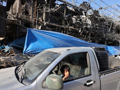 Un niño el interior de un vehículo ante un edificio destruido por un ataque israelí, este lunes en el campo de refugiados de Nuseirat, en el centro de la franja de Gaza.