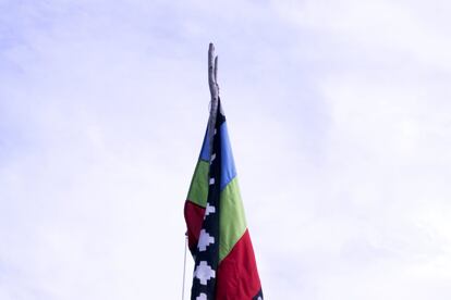 Bandera del pueblo mapuche sostenida en un asta de madera. El rojo simboliza la fuerza y el poder, recuerdo de la historia de lucha del pueblo mapuche. El verde representa la naturaleza y la madre tierra. El azul representa la vida, lo sagrado y lo espiritual.