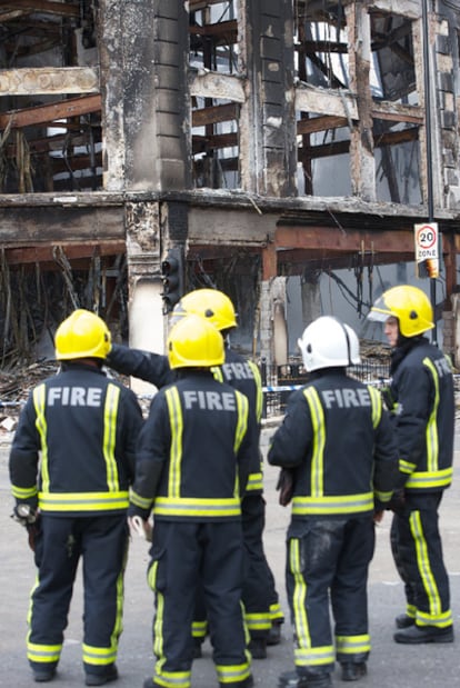 Varios bomberos observan los estragos del fuego en unos almacenes.