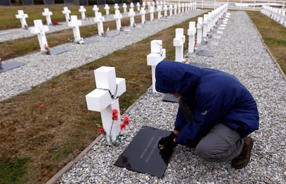 Un hombre junto a una de las tumbas del cementerio de Darwin en las islas Malvinas.