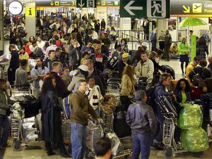 Cientos de pasajeros hacen cola ayer para facturar sus equipajes en la terminal T-1 del aeropuerto de Barajas.