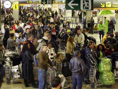 Cientos de pasajeros hacen cola ayer para facturar sus equipajes en la terminal T-1 del aeropuerto de Barajas.