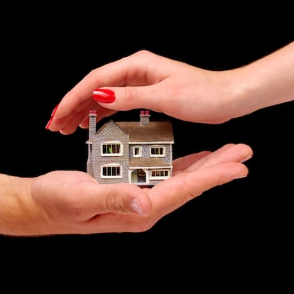 Hands protecting house on black background