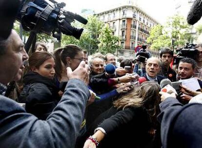 Los periodistas <i>acorralan</i> a Fraga a su llegada a la sede del PP. A la izquierda, con la mano alzada, el hombre que le pidió que dimitiera.