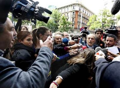 Los periodistas <i>acorralan</i> a Fraga a su llegada a la sede del PP. A la izquierda, con la mano alzada, el hombre que le pidió que dimitiera.