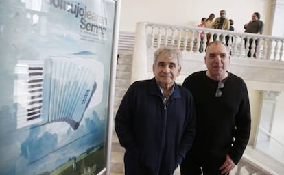 El escritor Bernardo Atxaga y el director Fernando Bernués ante el cartel del filme 'El hijo del acordeonista'.