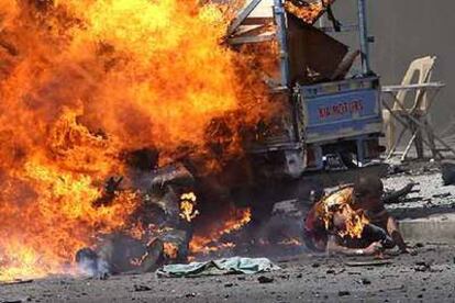 Un hombre se quema y otro se arrastra lejos del fuego segundos despus de la explosin de un coche bomba ayer en Bagdad.