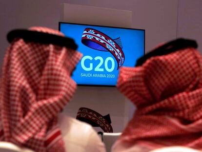 Dos funcionarios saudíes siguen en un televisor la reunión de ministros de Finanzas y gobernadores de los bancos centrales del G20 en Riad.
