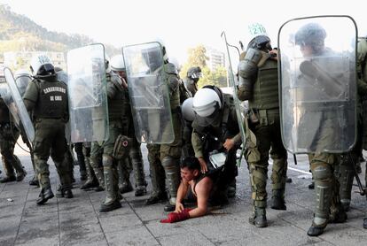 Un policía revisa el contenido de la mochila de un manifestante detenido durante la protesta en Santiago.