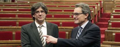 El expresidente Artur Mas (d) y el nuevo presidente de la Generalitat, Carles Puigdemont (d), se saludan a la finalizaci&oacute;n del pleno celebrado esta tarde en el Parlament de catalu&ntilde;a.