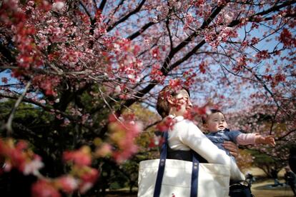 Un bebé de 7 meses contempla los cerezos en flor junto a su madre en un parque de Tokio (Japón), el 14 de marzo de 2018.