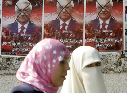 Dos mujeres palestinas caminan frente a carteles de Mahmud Abbas en la franja de Gaza.