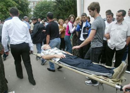 Los camilleros evacuan a un familiar de uno de los rehenes, derrumbado por la tensa espera.