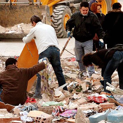 Vecinos del barrio del Carmel buscan objetos personales entre los escombros del edificio derruido.