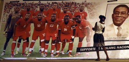 Una mujer mira un póster de la selección de fútbol de Guinea Ecuatorial junto al presidente Obiang.