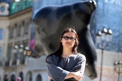 El artista chino Li Chen posa frente a una de sus doce estatuas