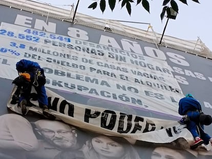 Dos miembros del Movimiento por la Vivienda de Madrid se descolgaban este viernes por la fachada del edificio donde está la lona de Desokupa para pegar carteles encima.