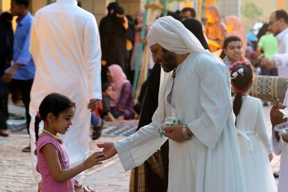 Un hombre reparte caramelos entre los niños tras las oraciones matutinas del Eid al-Adha en la mezquita Rey Abdul Aziz en Riad, Arabia Saudí, el 21 de agosto de 2018.