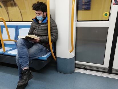 Josu Rodríguez  lee el libro de Eduardo de Bustos de filosofía 'La metáfora: ensayos transdisciplinares' en el Metro de Madrid