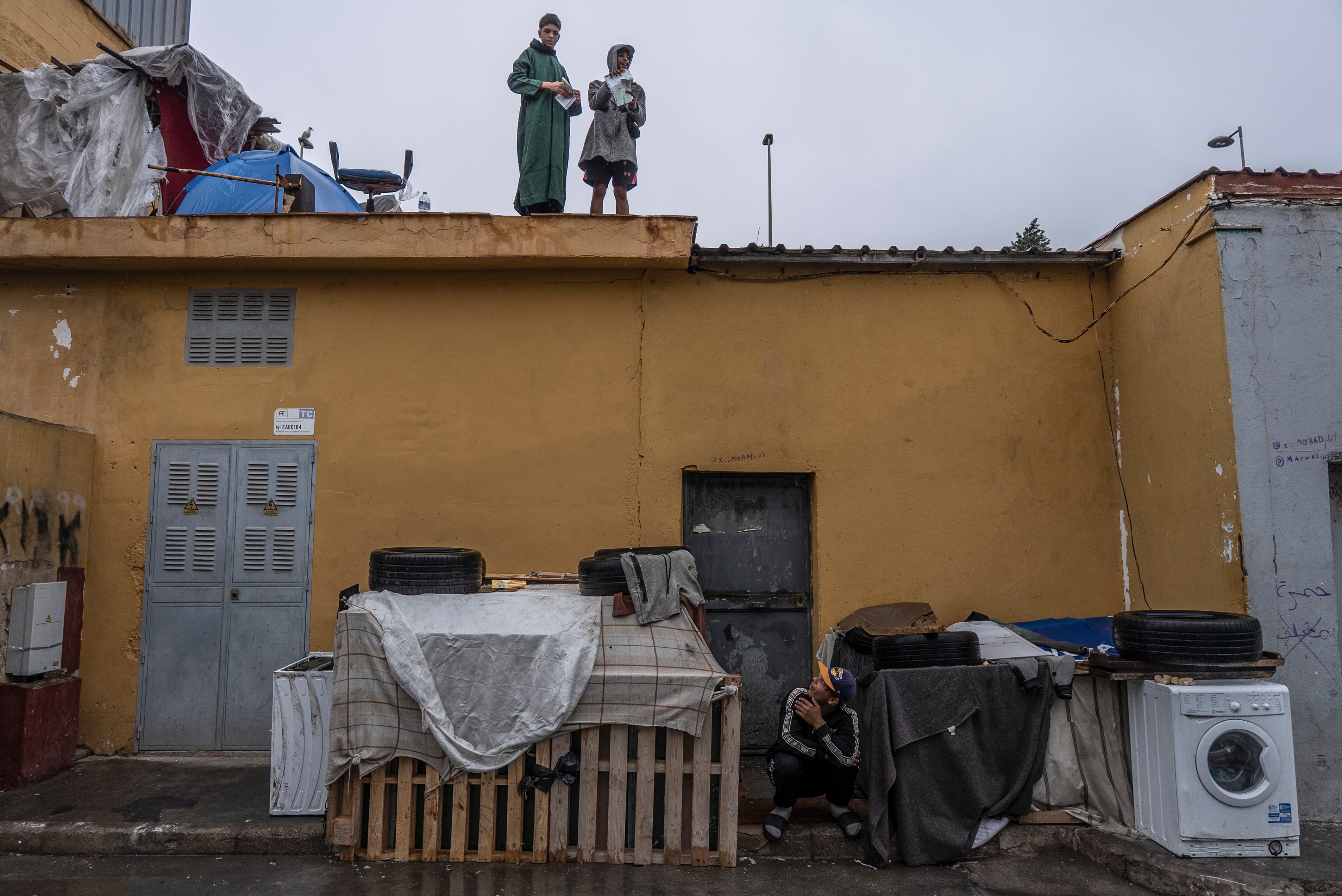 Jóvenes migrantes marroquíes mantienen una conversación con otro compañero desde el tejado de un edificio dentro del polígono industrial cercano a El Tarajal, en Ceuta, España, el 27 de septiembre.