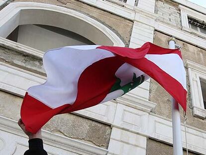 Un empleado coloca la bandera libanesa en la embajada abierta ayer por primera vez en Damasco.