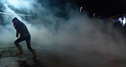 Un refugiado de Calais intenta ponerse a resguardo del gas lacrimógeno.