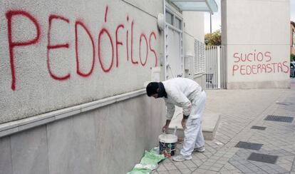 Un hombre cubre una pintada en la parroquia donde ejercía el padre Román.